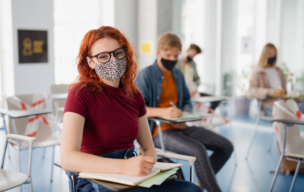 Portrait of university student in classroom indoors, coronavirus and back to normal concept.